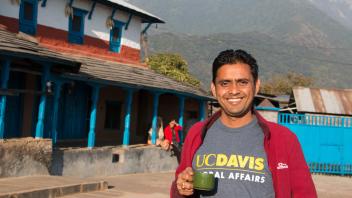 Student with a UC Davis Global Affairs t-shirt standing in front of a building