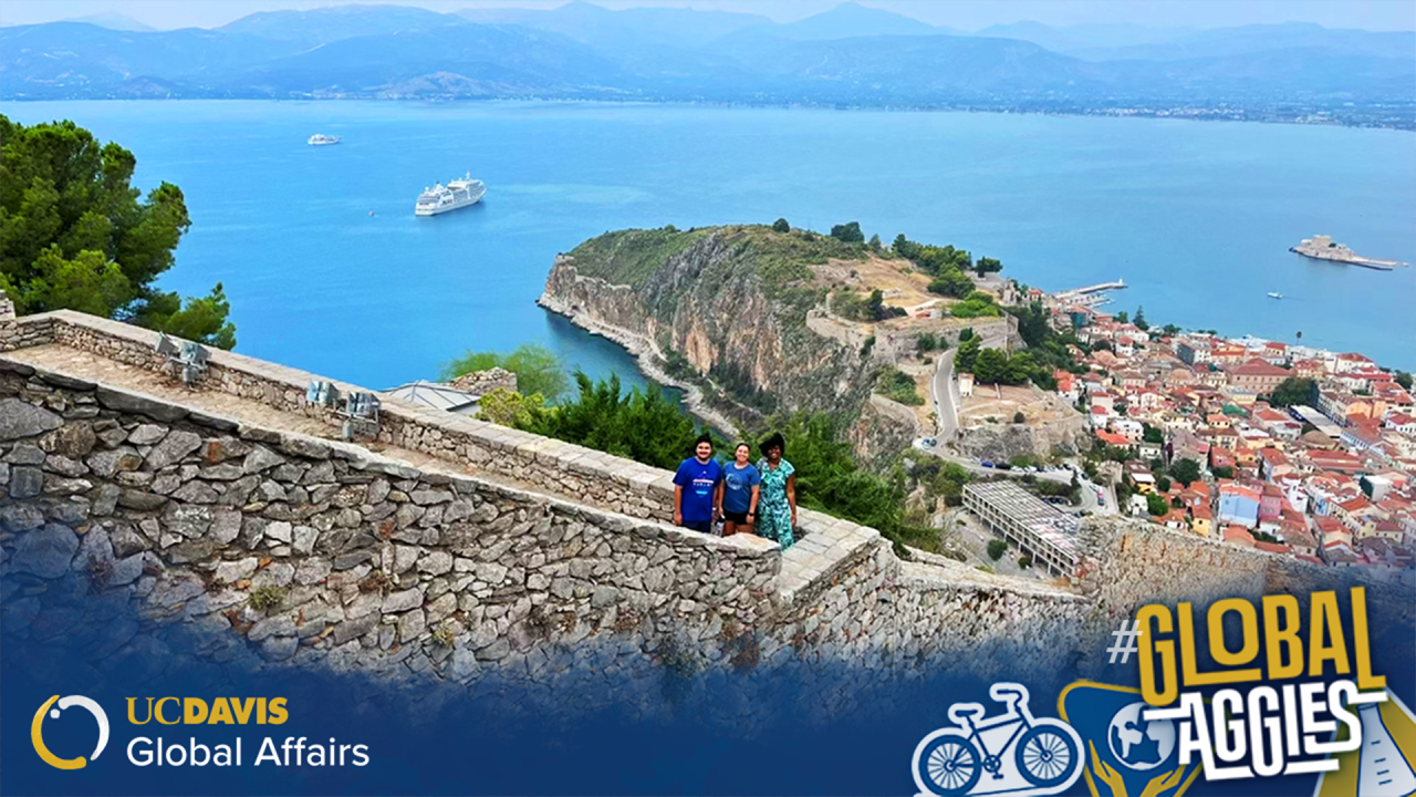 Photo of three students standing on a stone staircase overlooking the water