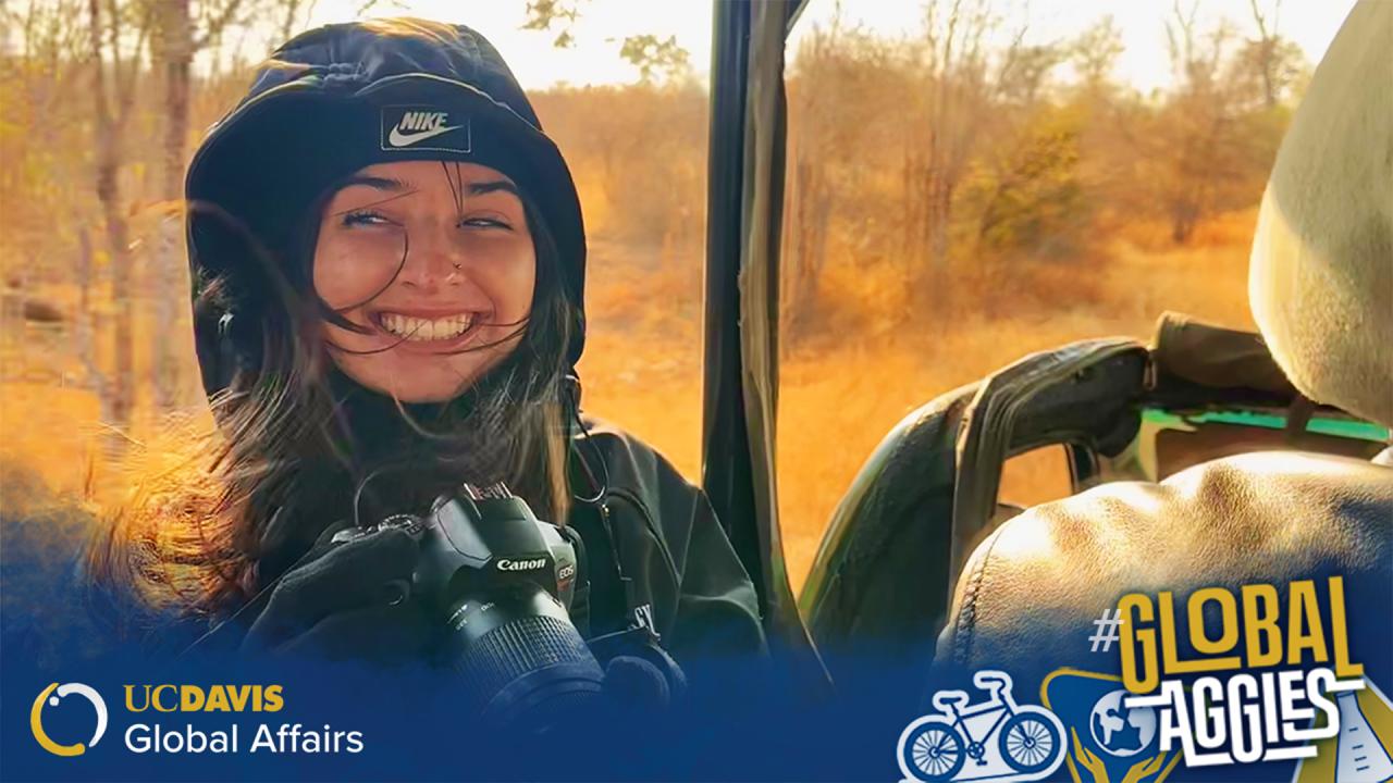 Student smiling in a vehicle with a camera, dry landscape in the background, and UC Davis Global Affairs branding at the bottom.