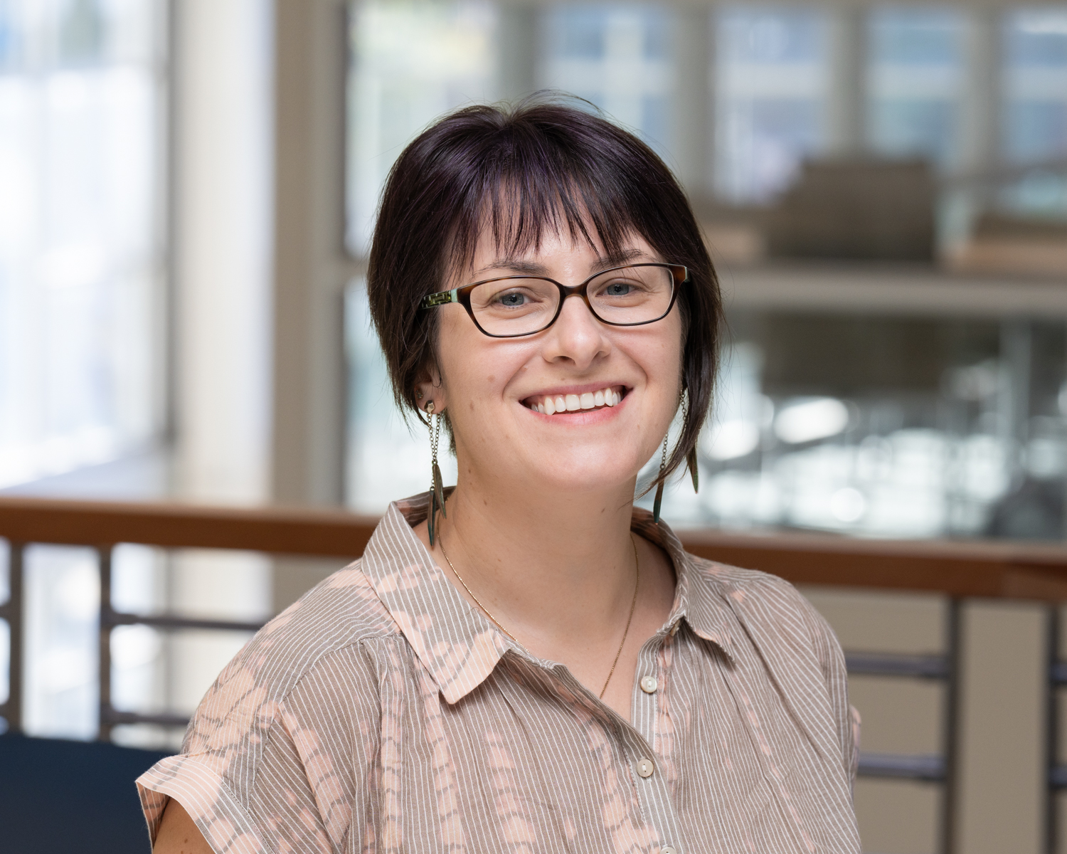 Jessica smiles in a short-sleeve button up inside the International Center.