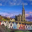 Colorful seaside row houses with a tall stone church spire at dusk