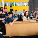 Group of students sit around a table and smile for the camera.