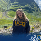 UC Davis student Anya Nygaard smiles at the camera wearing a UCD sweatshirt with the Scottish Highlands in the background. A blue watercolor overlay with Global Aggies is over the bottom of the photo.