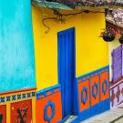 Colorful houses with ornate designs and hanging flowers line a cobblestone street.