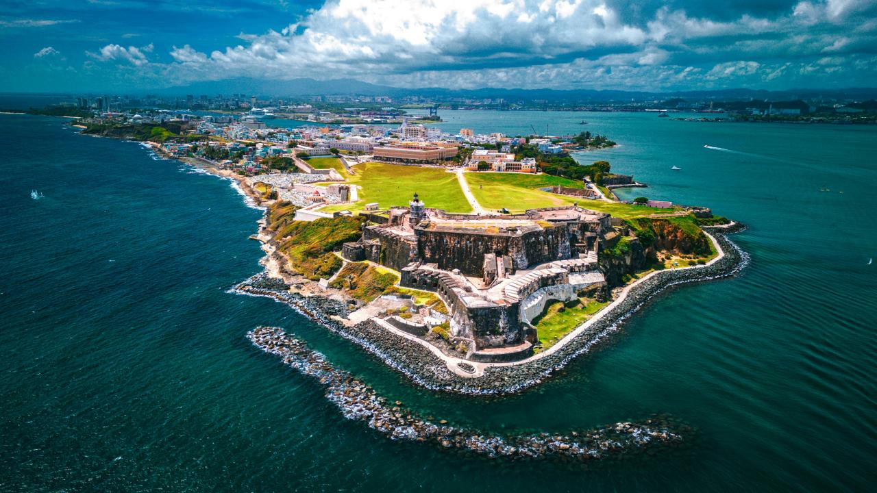 Aerial photo of coastal fortress on rocky promontory with green lawns and blue sea